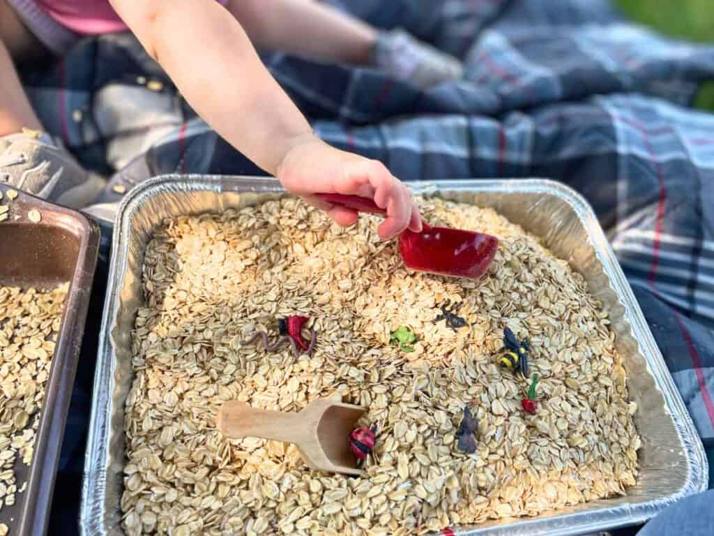 a toddler playing with a bug themed sensory bin