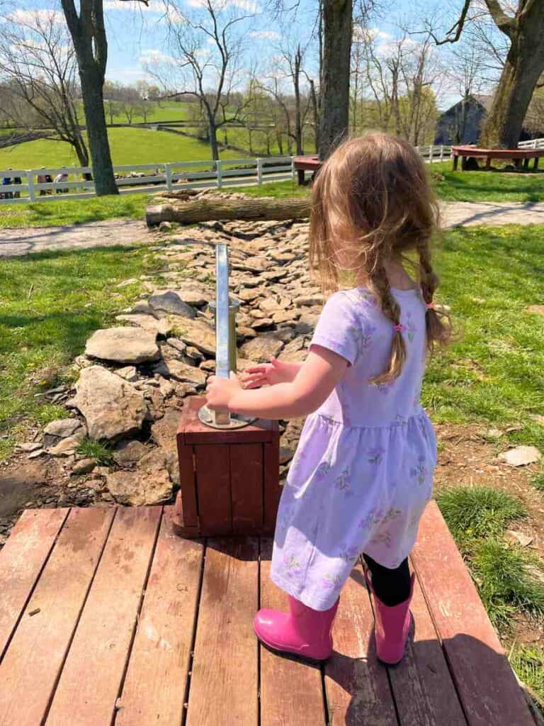 preschooler playing with water pump at Shaker Village of Pleasant Hill, KY