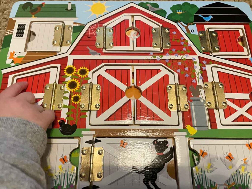 toddler playing with latch barn