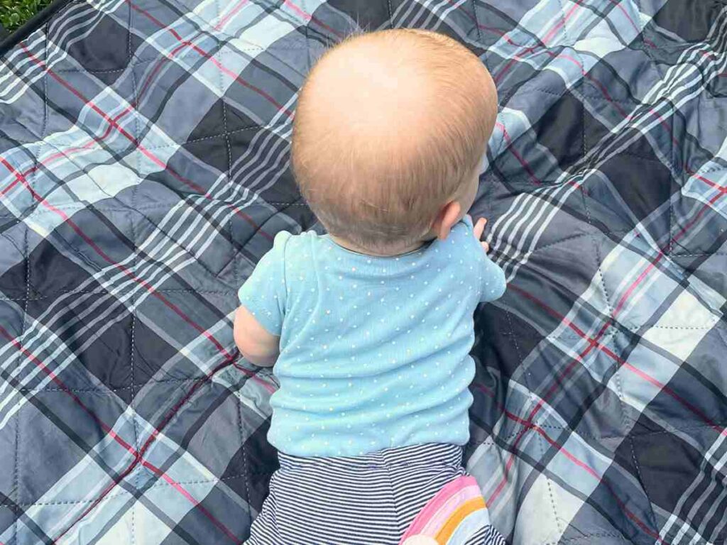 baby stretching out on a picnic blanket